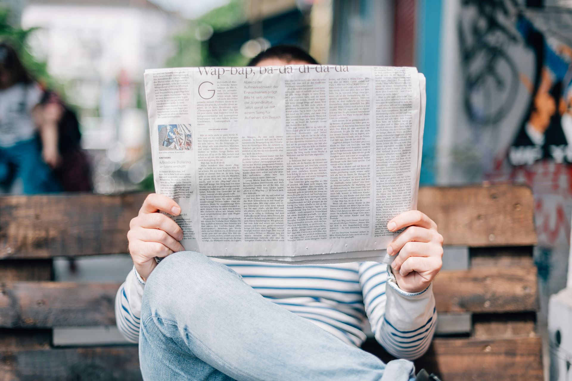 A person reading a newspaper with their face hidden